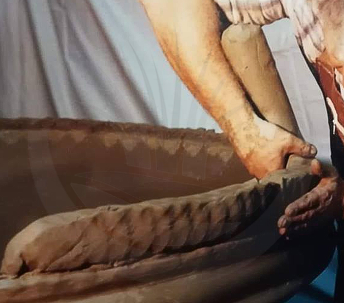 Artigiano tira il colombino per realizzare una grossa conca in terracotta